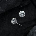 Close-up of luxury diamond earrings on textured black stone, showcasing elegance.