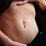 Close-up image showcasing a pierced belly button adorned with jewelry on smooth skin.