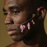 Portrait of a man with bleeding heart flower accentuating his face, creating a serene, artistic expression.